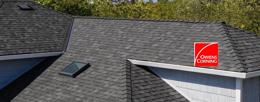 Roofing installation featuring Owens Corning shingles on a residential house with a skylight.